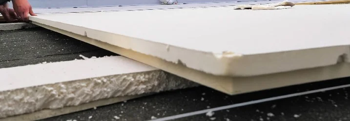 Person verlegt Dämmung auf Dach